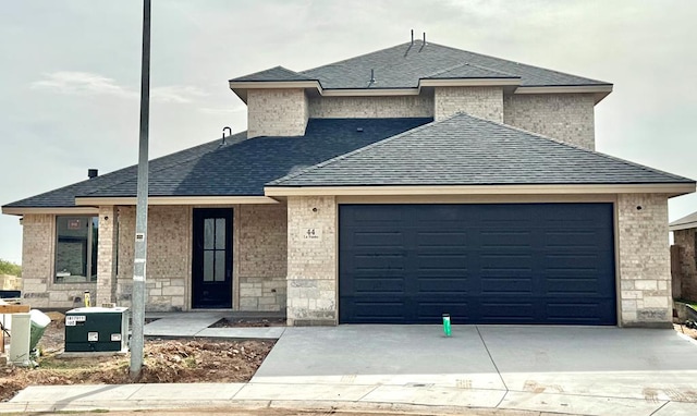 44 La Fauna Dr, Odessa, TX 79765 - view of front facade featuring roof with shingles, a garage, concrete driveway, and stone siding