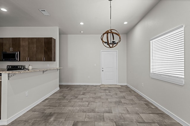 2227 W 3rd St, Odessa, TX 79763 - kitchen with stainless steel microwave, a kitchen bar, dark brown cabinets, a chandelier, and recessed lighting