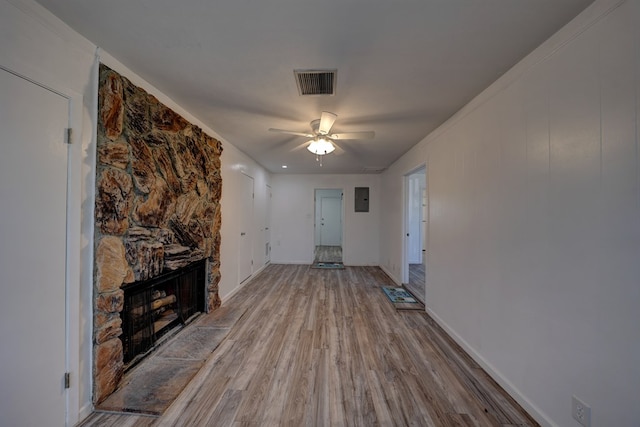 1500 S Bruce Ave, Monahans, TX 79756 - unfurnished living room with wood finished floors, ceiling fan, a stone fireplace, and electric panel