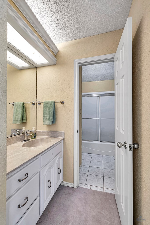 6415 San Mateo Ln, Odessa, TX 79762 - bathroom with vanity, tile patterned flooring, a textured wall, enclosed tub / shower combo, and a textured ceiling