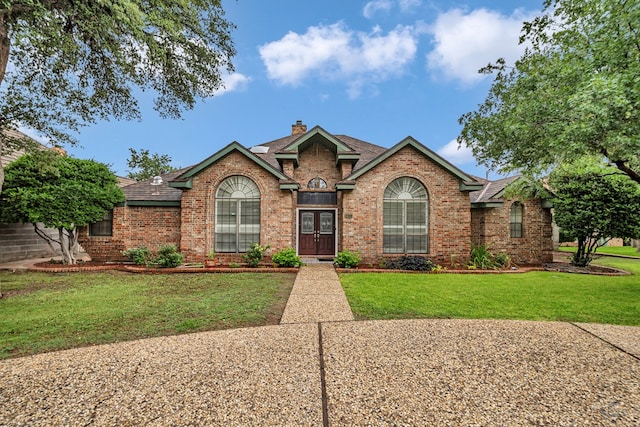 6415 San Mateo Ln, Odessa, TX 79762 - view of front facade with brick siding, a chimney, a front yard, and french doors