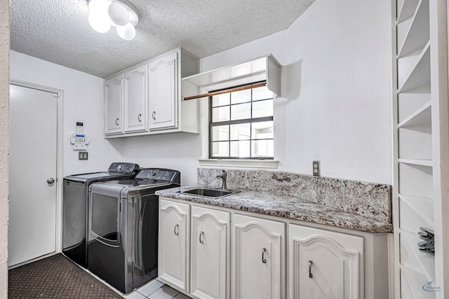 6415 San Mateo Ln, Odessa, TX 79762 - laundry area featuring washer and clothes dryer, cabinet space, a textured ceiling, and light tile patterned flooring