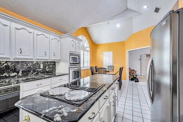 6415 San Mateo Ln, Odessa, TX 79762 - kitchen with stainless steel appliances, a kitchen island, a textured ceiling, vaulted ceiling, and light tile patterned floors