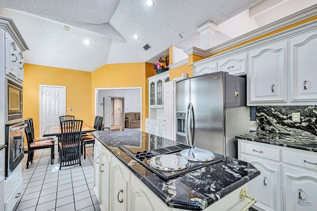 6415 San Mateo Ln, Odessa, TX 79762 - kitchen with stainless steel appliances, a center island, light tile patterned floors, glass insert cabinets, and dark stone counters