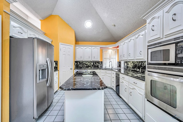 6415 San Mateo Ln, Odessa, TX 79762 - kitchen with stainless steel appliances, lofted ceiling, a center island, light tile patterned flooring, and a textured ceiling