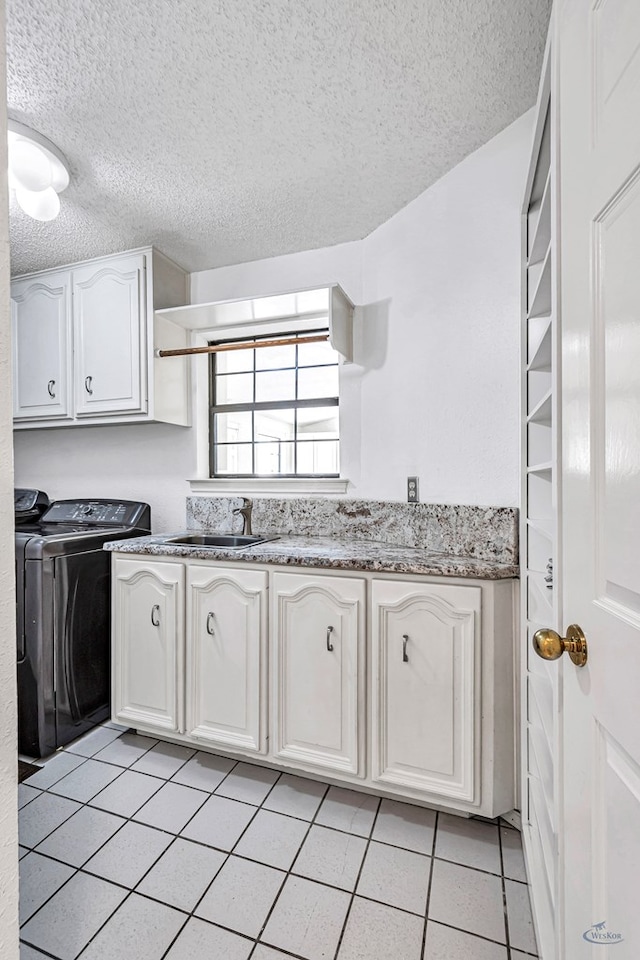 6415 San Mateo Ln, Odessa, TX 79762 - kitchen featuring a textured ceiling, light tile patterned floors, washing machine and dryer, white cabinetry, and light stone counters