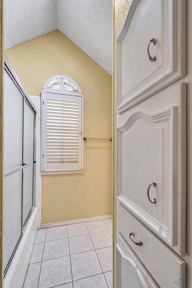 6415 San Mateo Ln, Odessa, TX 79762 - bathroom featuring lofted ceiling, a textured ceiling, tile patterned floors, and bath / shower combo with glass door