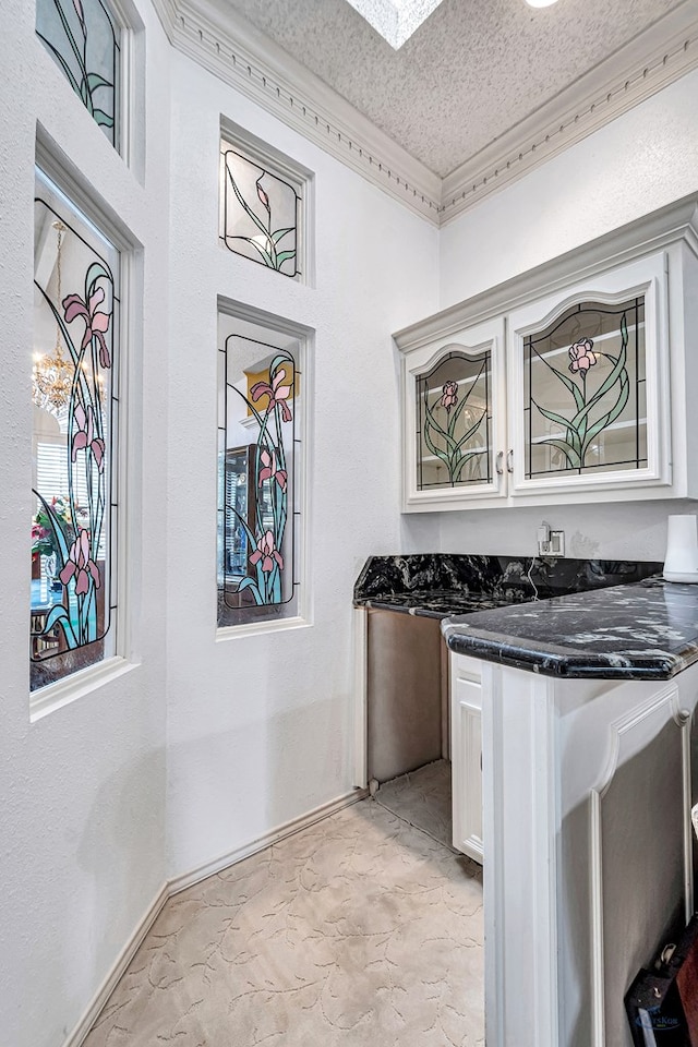 6415 San Mateo Ln, Odessa, TX 79762 - kitchen with a textured ceiling, white cabinets, a textured wall, and crown molding