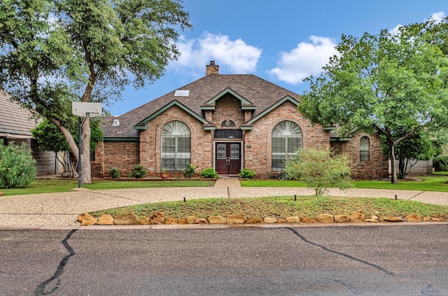 6415 San Mateo Ln, Odessa, TX 79762 - traditional-style house featuring brick siding, a chimney, and french doors