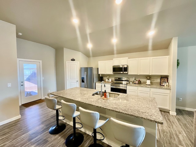 1311 Red Cliff Ave, Odessa, TX 79765 - kitchen featuring appliances with stainless steel finishes, light wood finished floors, white cabinets, a kitchen breakfast bar, and a kitchen island with sink