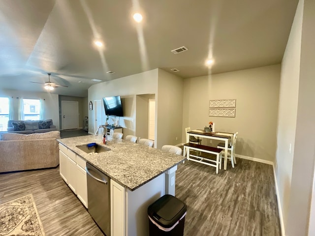 1311 Red Cliff Ave, Odessa, TX 79765 - kitchen with stainless steel dishwasher, open floor plan, a center island with sink, white cabinets, and wood finished floors