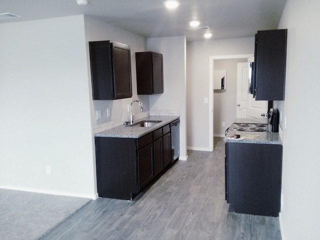 kitchen with baseboards, a sink, light wood finished floors, and dishwasher