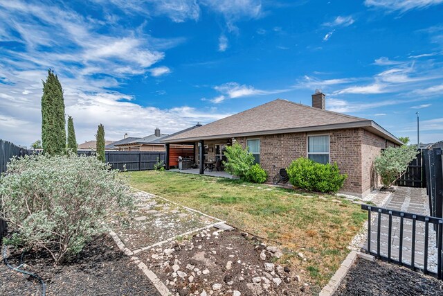 811 E 97th Ct, Odessa, TX 79765 - back of house featuring a patio area, brick siding, roof with shingles, and a chimney
