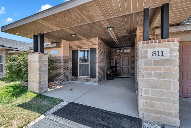 811 E 97th Ct, Odessa, TX 79765 - view of exterior entry featuring brick siding and a patio