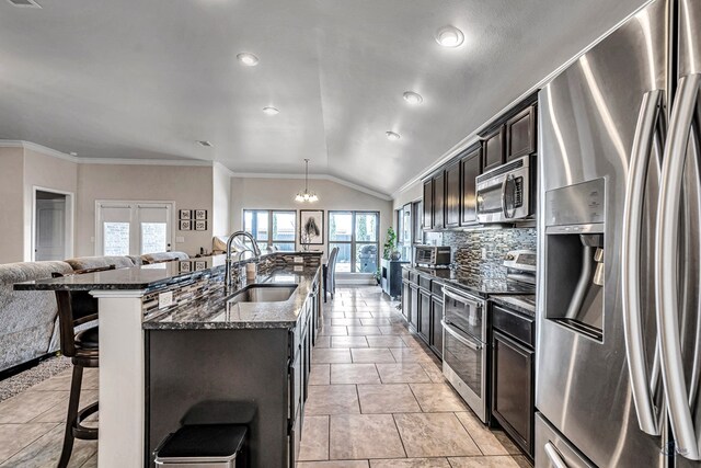 811 E 97th Ct, Odessa, TX 79765 - kitchen with appliances with stainless steel finishes, a kitchen breakfast bar, a sink, dark stone counters, and decorative backsplash