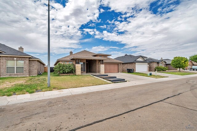 811 E 97th Ct, Odessa, TX 79765 - view of front of home featuring an attached garage, brick siding, driveway, a front yard, and a residential view