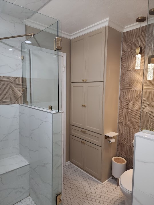 bathroom with crown molding, toilet, and a marble finish shower