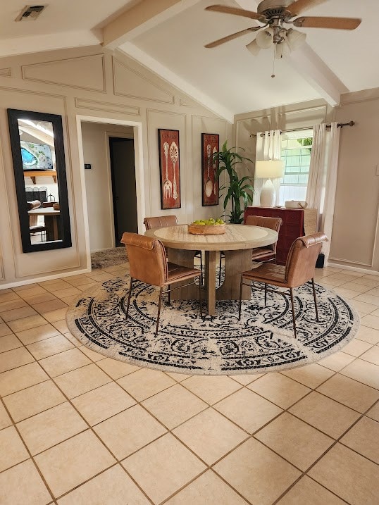 dining room featuring ceiling fan, visible vents, light tile patterned flooring, and vaulted ceiling with beams
