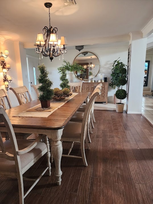 dining area with a chandelier, crown molding, and wood finished floors