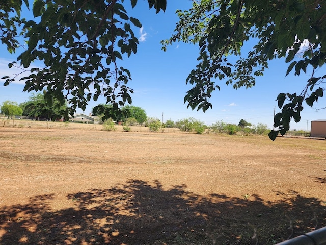 view of yard with fence and a rural view