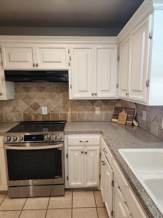 kitchen featuring a sink, electric range, white cabinets, under cabinet range hood, and light tile patterned flooring