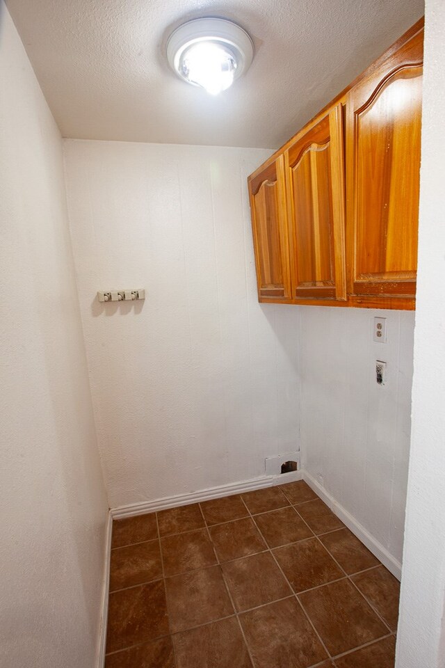 8731 Dublin Ave, Odessa, TX 79765 - laundry area featuring cabinet space, dark tile patterned flooring, washer hookup, and baseboards