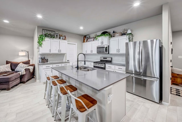8409 E County Rd 115, Midland, TX 79706 - kitchen featuring appliances with stainless steel finishes, a sink, decorative backsplash, white cabinets, and a kitchen bar
