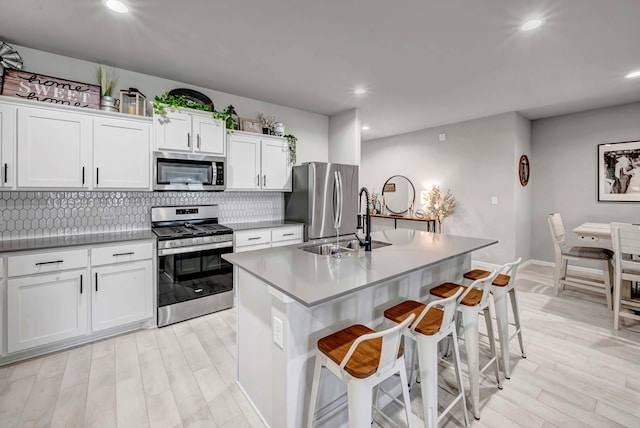 8409 E County Rd 115, Midland, TX 79706 - kitchen featuring stainless steel appliances, a sink, tasteful backsplash, white cabinets, and light wood-style floors