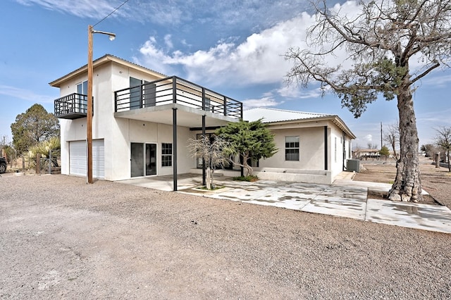 1007 E Texas St, Marfa, TX 79843 - back of house with a balcony, a garage, dirt driveway, and stucco siding