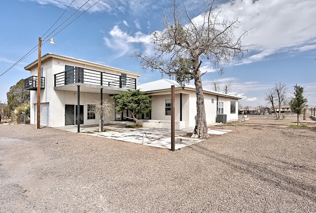 1007 E Texas St, Marfa, TX 79843 - view of front of property with a balcony, stucco siding, an attached garage, and gravel driveway