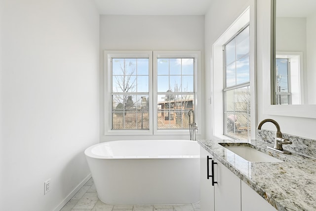1007 E Texas St, Marfa, TX 79843 - bathroom featuring marble finish floors, baseboards, a soaking tub, and vanity