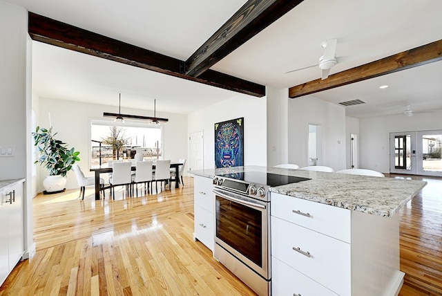 1007 E Texas St, Marfa, TX 79843 - kitchen featuring stainless steel electric range, ceiling fan, white cabinets, light wood finished floors, and beam ceiling