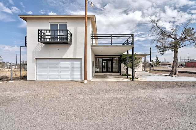 1007 E Texas St, Marfa, TX 79843 - view of front of home with a balcony, a garage, gravel driveway, and stucco siding
