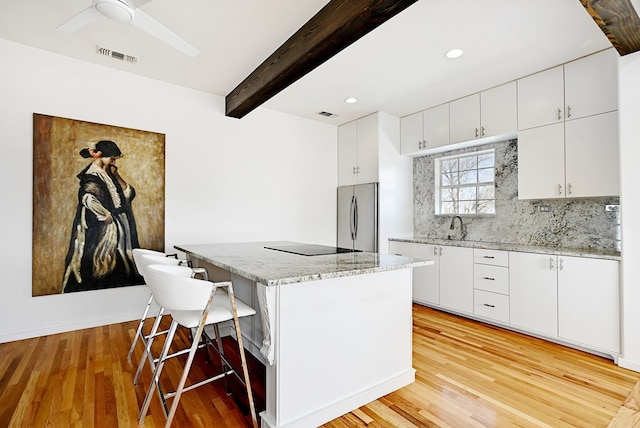 1007 E Texas St, Marfa, TX 79843 - kitchen featuring freestanding refrigerator, a breakfast bar area, a center island, beam ceiling, and decorative backsplash