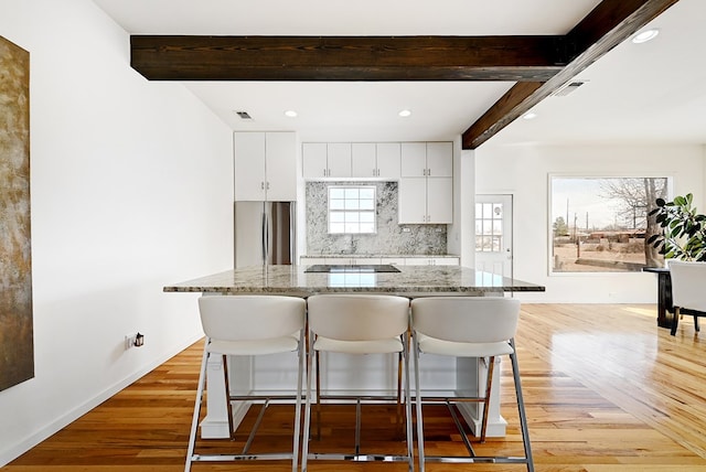 1007 E Texas St, Marfa, TX 79843 - kitchen featuring freestanding refrigerator, beamed ceiling, a kitchen bar, light wood-style flooring, and backsplash