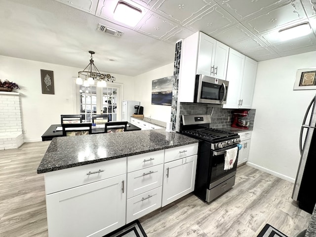 503 E Hendryx Ave, Alpine, TX 79830 - kitchen with stainless steel appliances, a peninsula, white cabinets, light wood-style flooring, and dark stone countertops