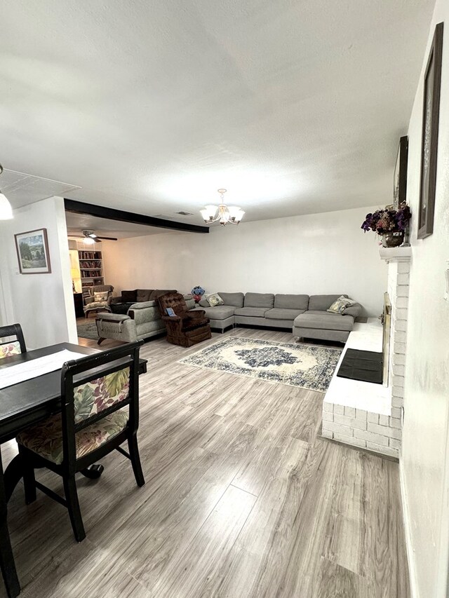 503 E Hendryx Ave, Alpine, TX 79830 - living area with a brick fireplace, light wood-style flooring, a chandelier, and ceiling fan