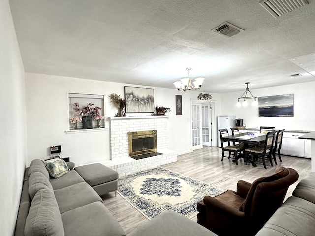 503 E Hendryx Ave, Alpine, TX 79830 - living area featuring a chandelier, wood finished floors, a fireplace, and a textured ceiling