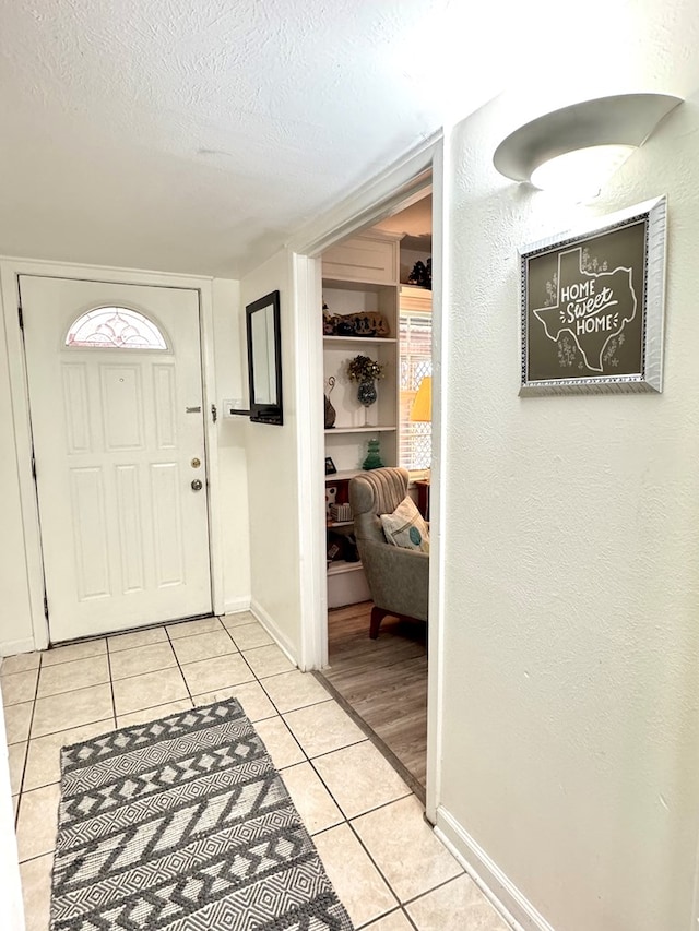 503 E Hendryx Ave, Alpine, TX 79830 - foyer entrance with light tile patterned floors, a textured ceiling, baseboards, and a textured wall