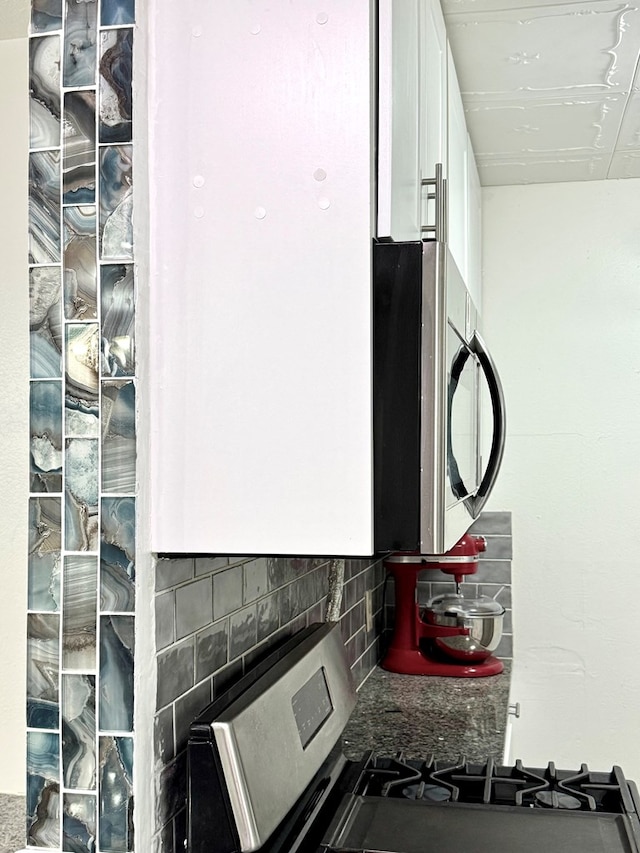 503 E Hendryx Ave, Alpine, TX 79830 - kitchen view of backsplash, range, white cabinets, and stainless steel microwave