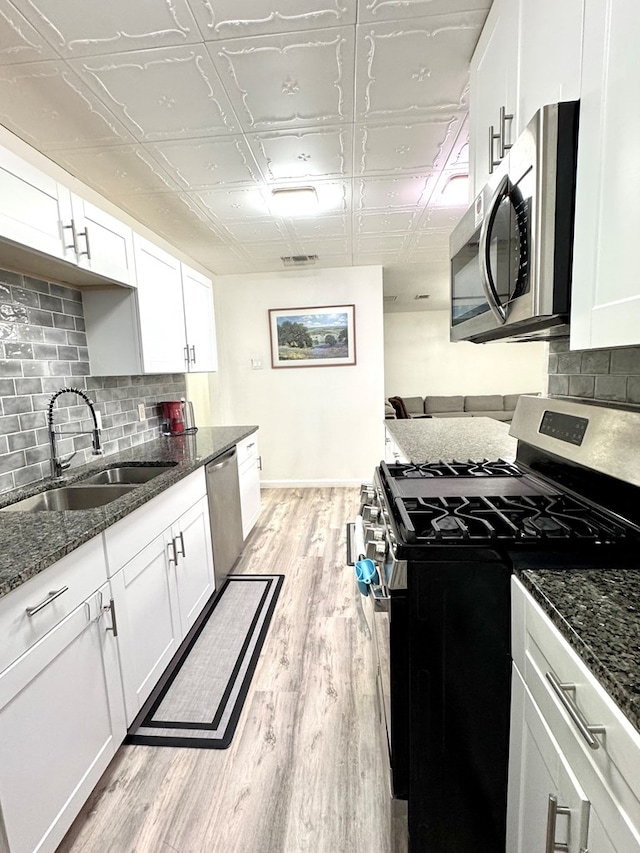 503 E Hendryx Ave, Alpine, TX 79830 - kitchen with stainless steel appliances, a sink, an ornate ceiling, white cabinets, and light wood-style flooring