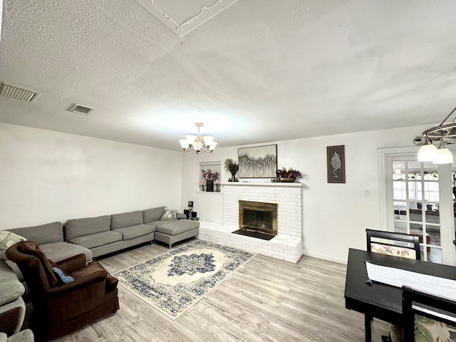 503 E Hendryx Ave, Alpine, TX 79830 - living room featuring a chandelier, wood finished floors, a brick fireplace, baseboards, and a textured ceiling