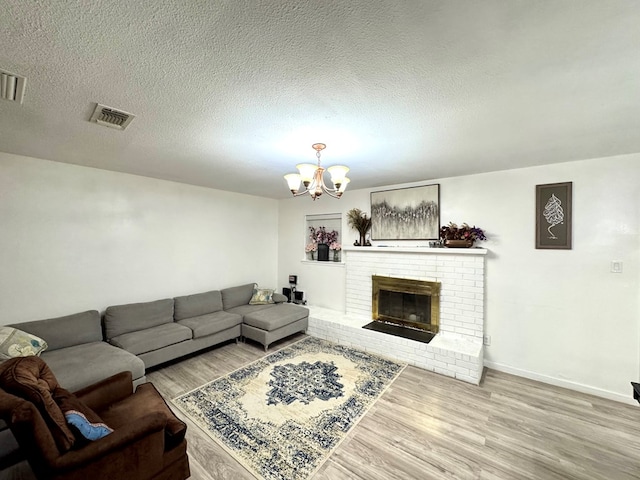 503 E Hendryx Ave, Alpine, TX 79830 - living room featuring wood finished floors, a chandelier, a brick fireplace, baseboards, and a textured ceiling