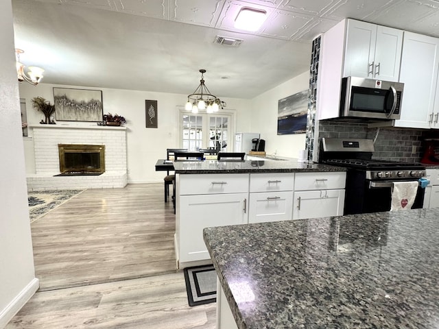 503 E Hendryx Ave, Alpine, TX 79830 - kitchen with appliances with stainless steel finishes, white cabinets, a peninsula, and light wood-style flooring