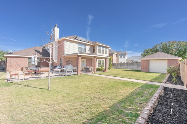 rear view of property featuring a lawn, solar panels, a garage, a patio area, and an outdoor structure