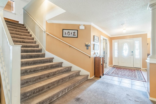 foyer entrance featuring light tile patterned floors, a textured ceiling, ornate columns, and crown molding