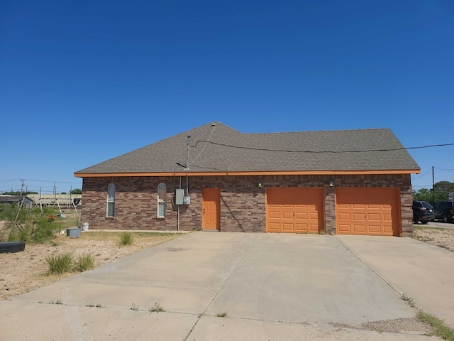 view of front of home with driveway, brick siding, roof with shingles, and a garage