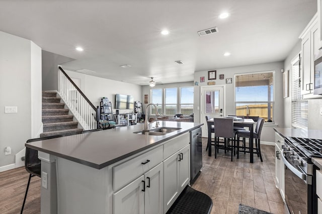 3102 Mearns Ct, Midland, TX 79705 - kitchen featuring appliances with stainless steel finishes, wood finished floors, a ceiling fan, a kitchen island with sink, and recessed lighting