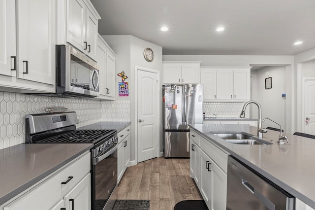3102 Mearns Ct, Midland, TX 79705 - kitchen with appliances with stainless steel finishes, light wood finished floors, white cabinets, backsplash, and recessed lighting