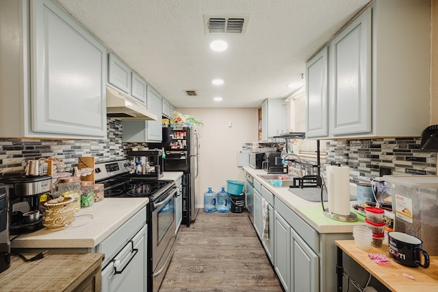 3946 Scott St, Odessa, TX 79762 - kitchen featuring appliances with stainless steel finishes, under cabinet range hood, light countertops, backsplash, and recessed lighting